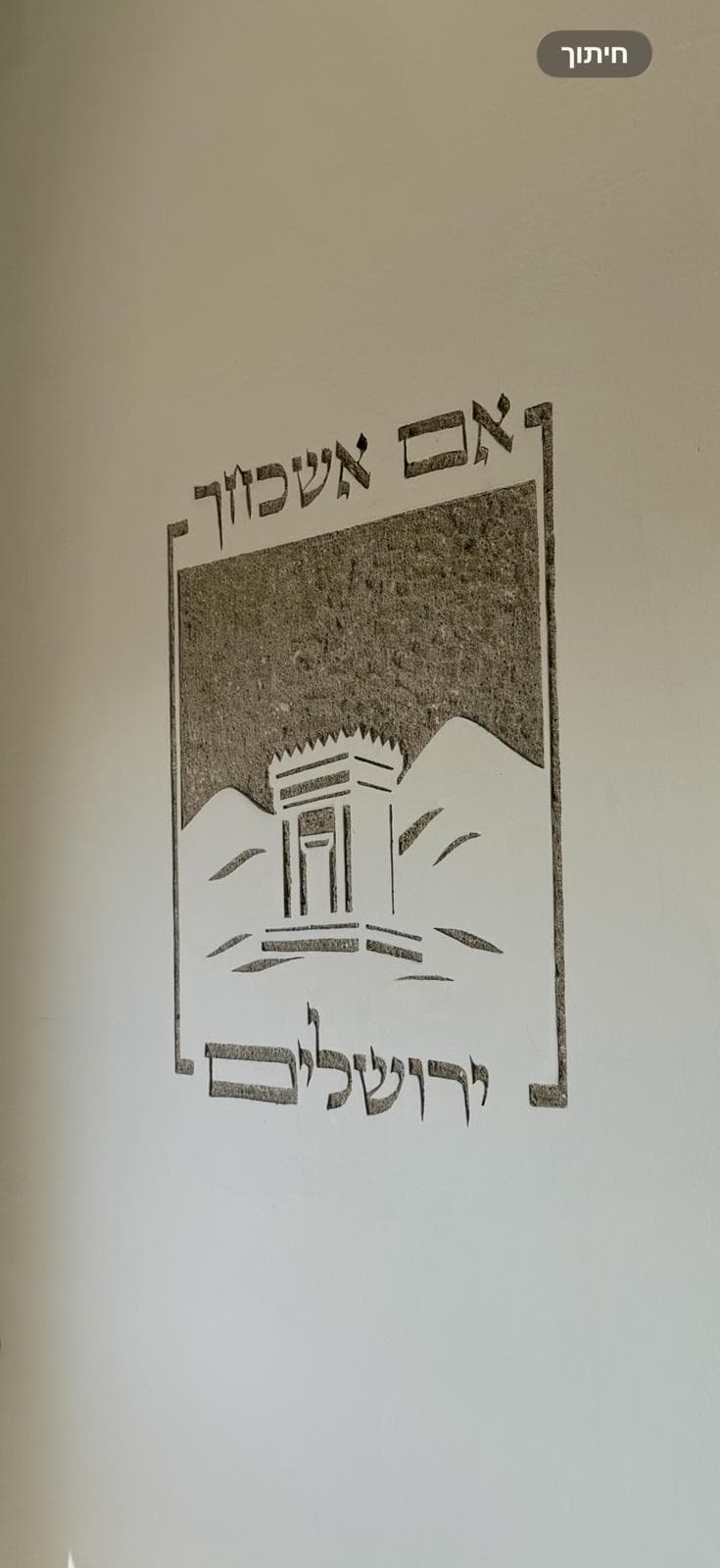 אמה על אמה חצובה בקיר לבן: בית המקדש על רקע הרים בתוך מסגרת, עם הכיתוב "אם אשכחך" ו"ירושלים".